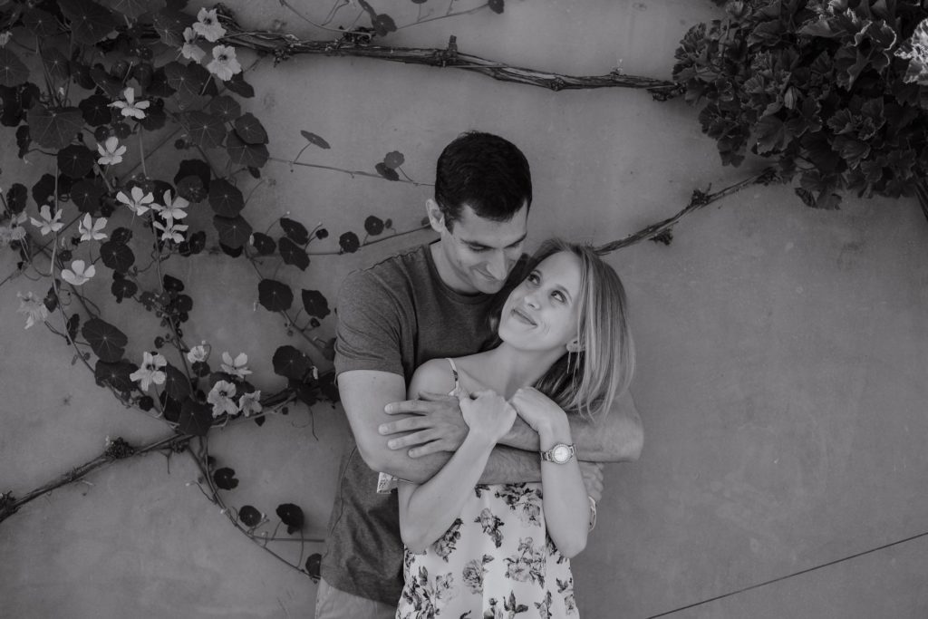 black and white photo of man and woman against wall in couples photoshoot