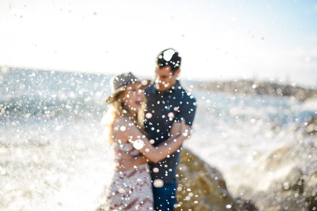 wave spraying embracing couple