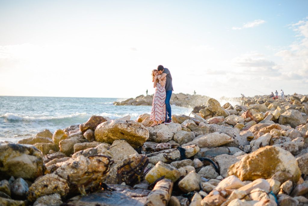 man and woman on rocks on beach at couples photoshoot