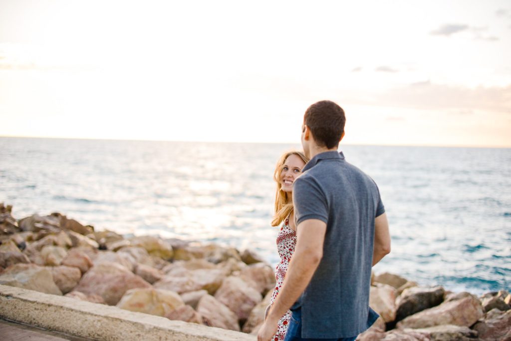 man and woman walking outdoors by rocks and water