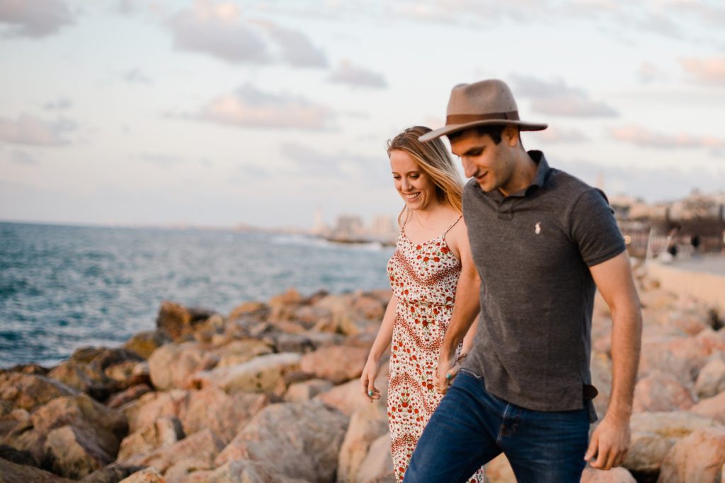 smiling couple walking among rocky beach