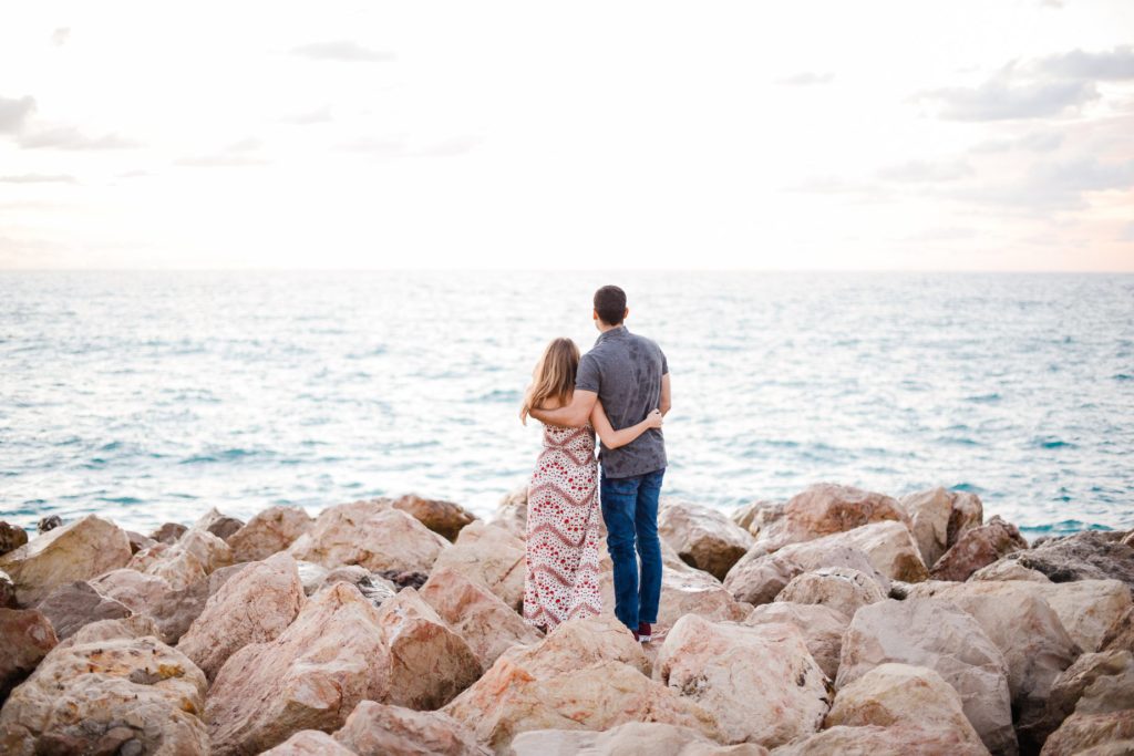 man and woman standing on rocky beach for a couples photoshoot