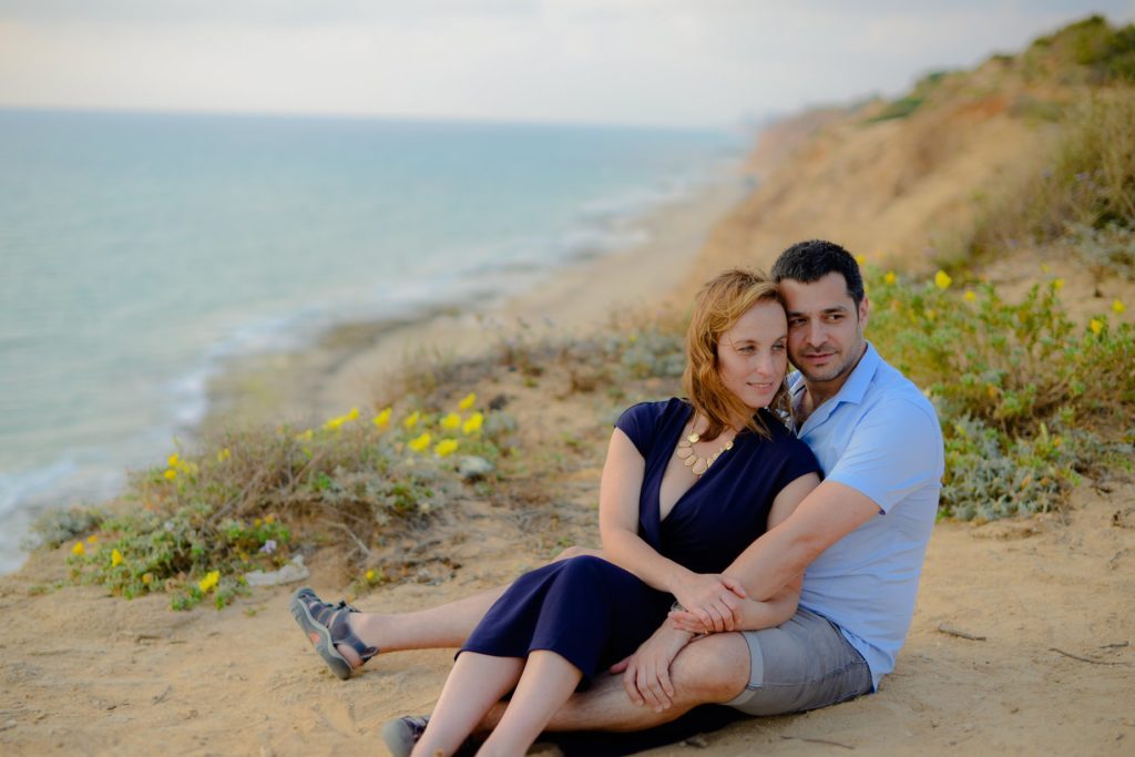 couple sitting and embracing on beach engagement photoshoot