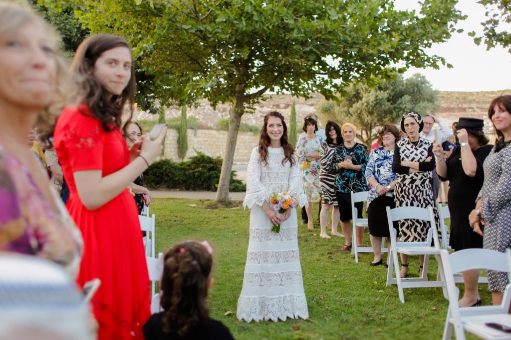 smiling bride walking down outdoor aisle with bouquet at wedding photography session