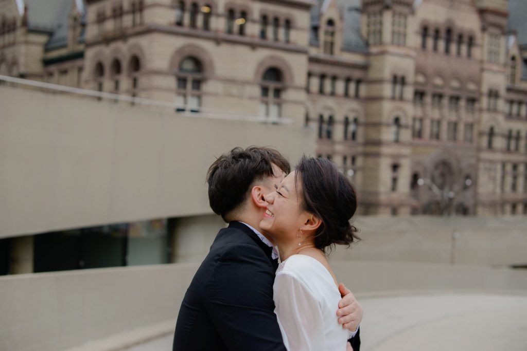 bride and groom hugging in front of toronto's city hall