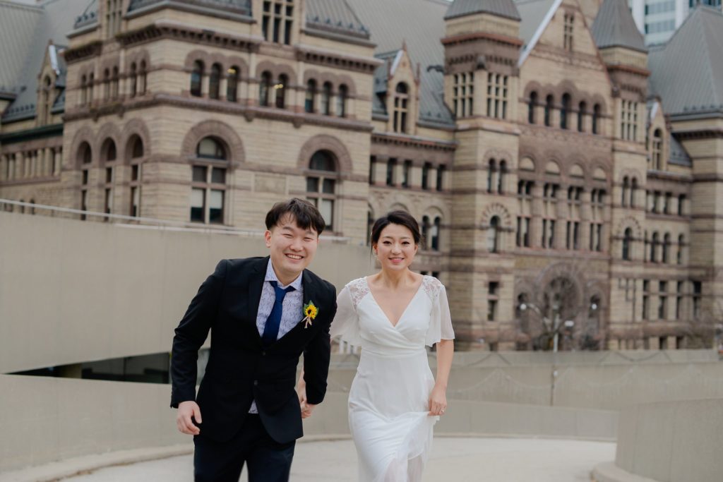 smiling bride and groom in front of toronto's city hall