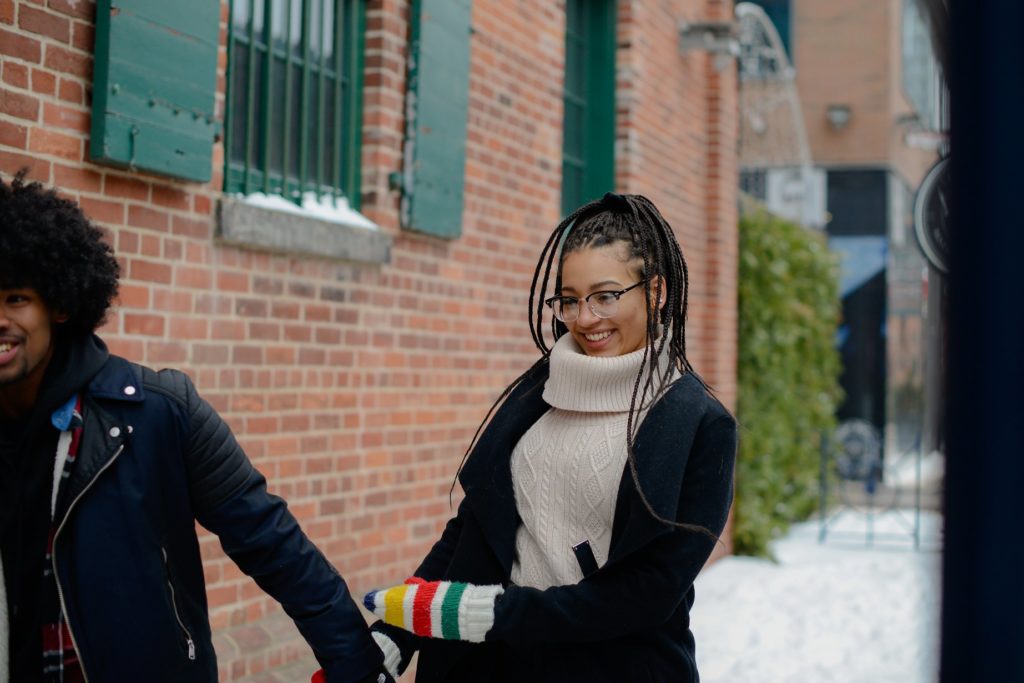 woman with braids smiling and holding hands with man 