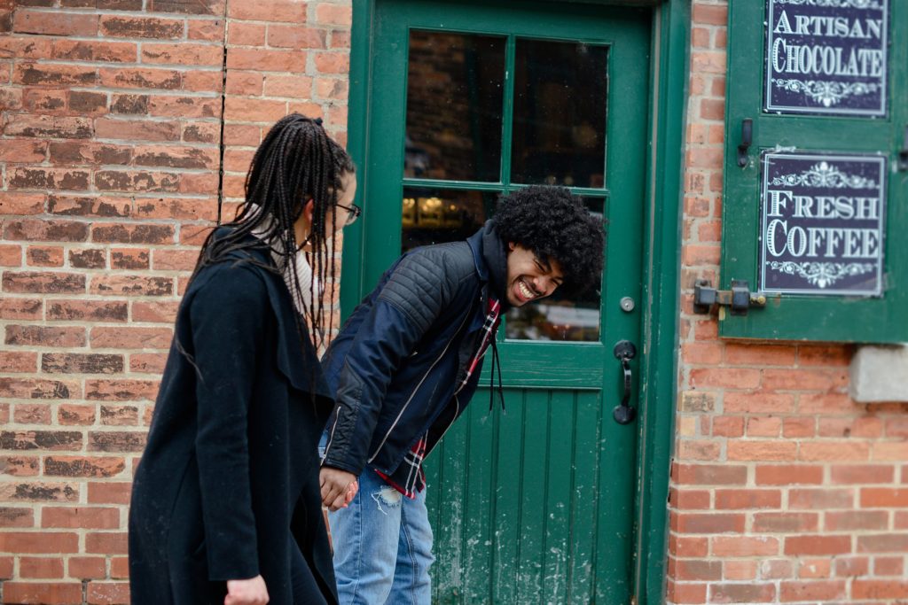 laughing couple against brick wall in front of green door