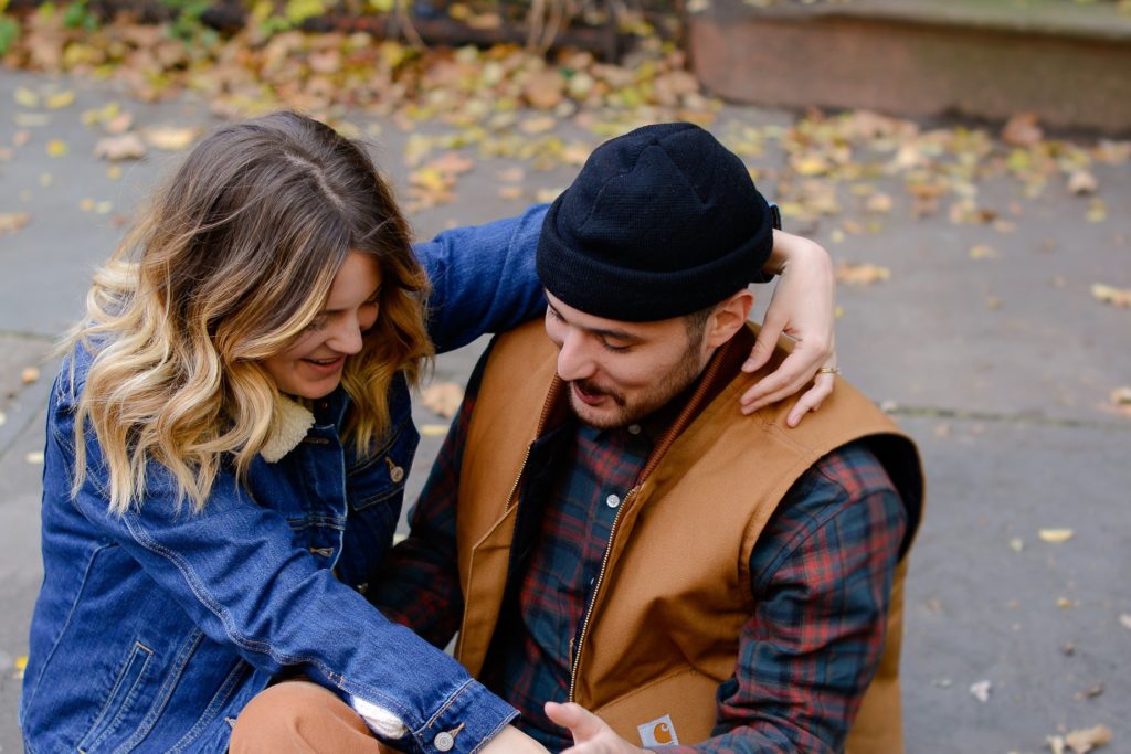 close up shot of couple hugging outside in denim jacket and brown vest at engagement photoshoot