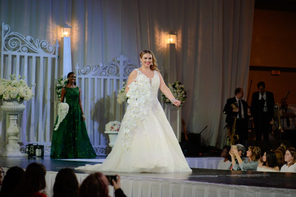 Bride in long white dress with white bouquet on runway at Canada's Bridal Show 2019